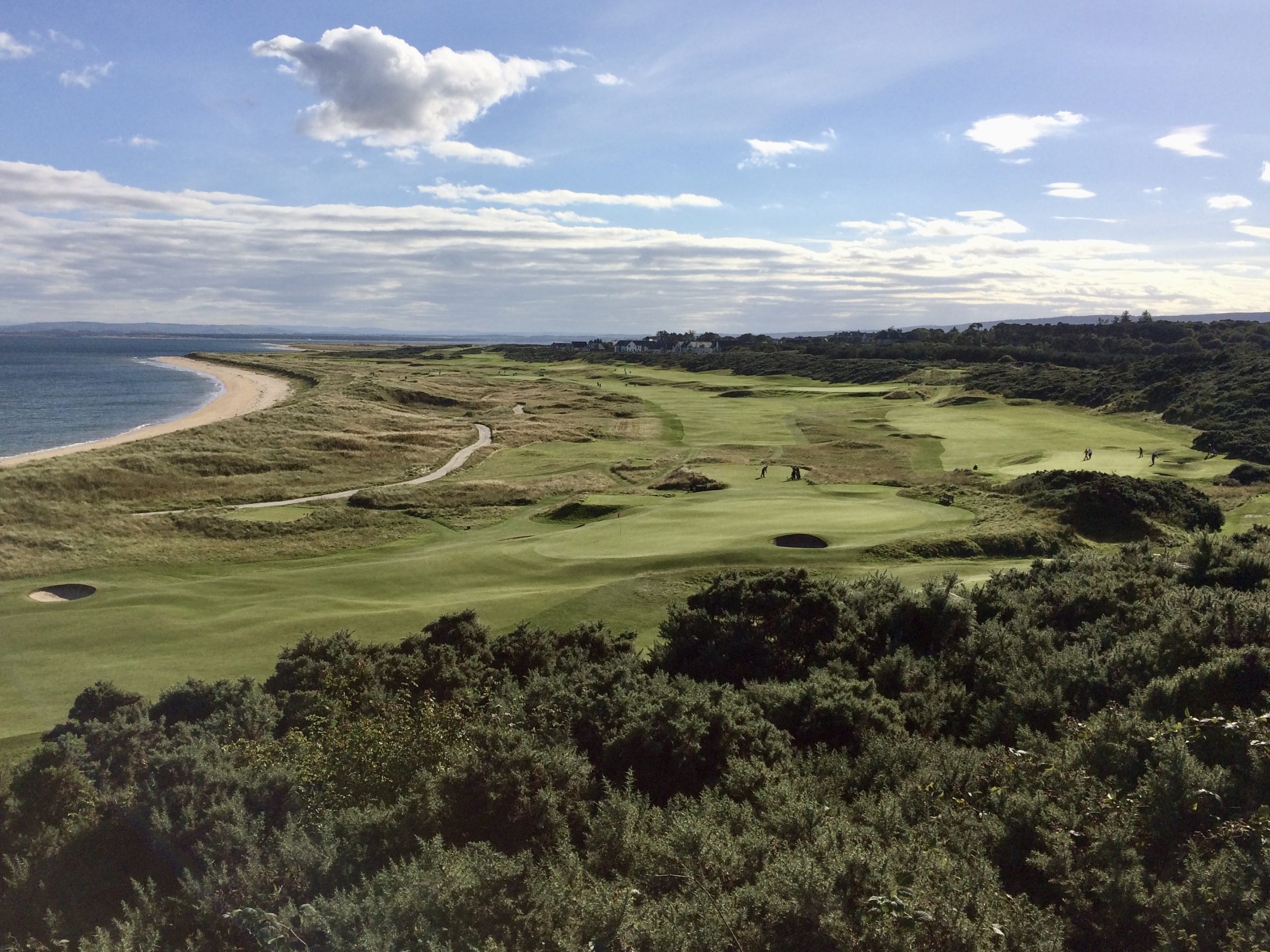 Panoramic view from the elevated tee at Royal Dornoch, looking across the championship links course with rolling fairways and sweeping Highland coastline.