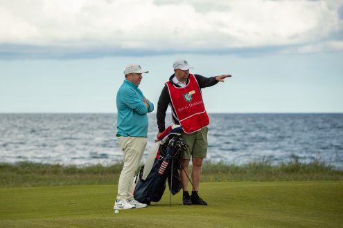 Royal Dornoch caddie giving advice to a golfer during his round