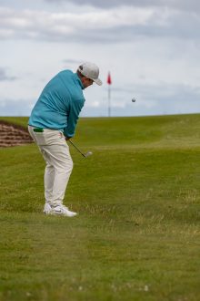 Golfer playing a chip shot towards the 13th green at Royal Dornoch